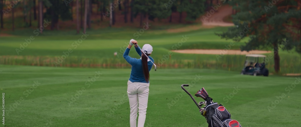 Caucasian female playing golf, striking a ball during the course Caucasian female playing golf, striking a ball during the course