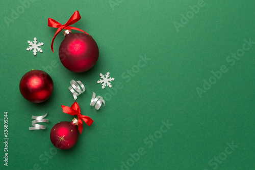 Christmas ball toys and confetti on color background, top view