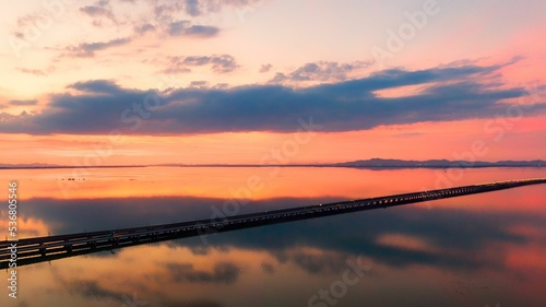 Scenic view of Shishu lake and bridge at sunset with the yellow reflection of the sky on the water photo
