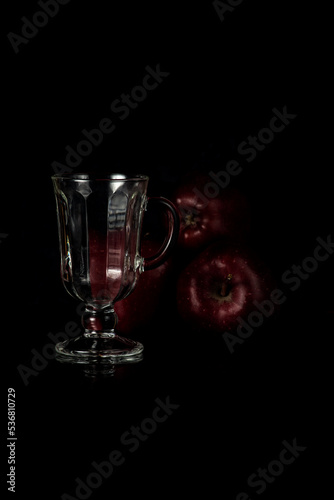 photo red apples and a glass tumbler on a dark background