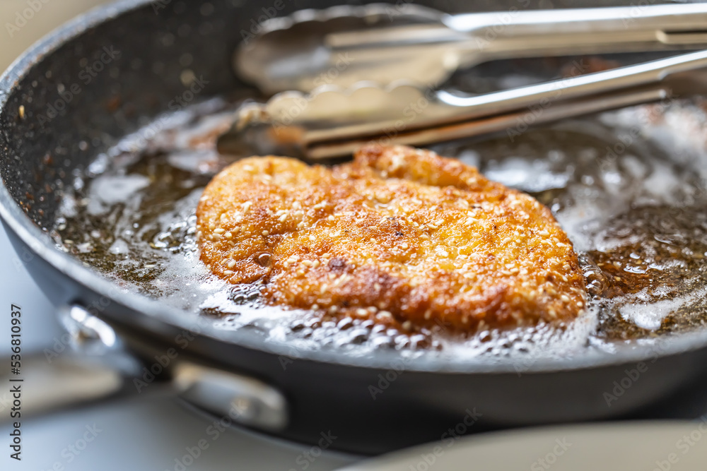 Schnitzel frying in a hot pan finished to golden crispy skin
