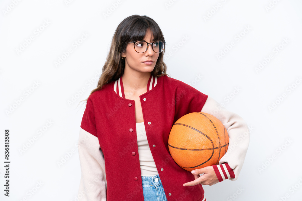 Young caucasian woman playing basketball isolated on white background looking to the side