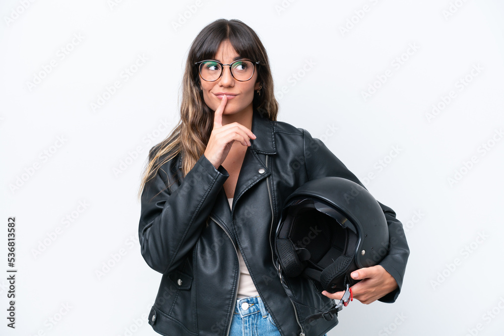 Young caucasian woman with a motorcycle helmet isolated on white background having doubts while looking up