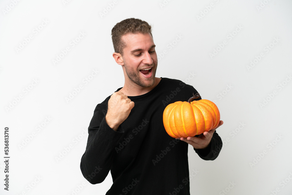 Young caucasian man holding a pumpkin isolated on white background celebrating a victory Young caucasian man holding a pumpkin isolated on white background celebrating a victory