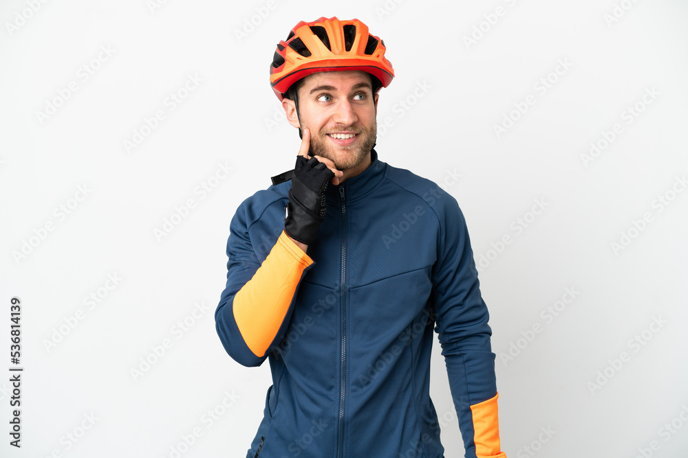 Young cyclist man isolated on white background thinking an idea while looking up