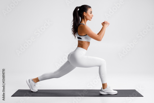 Fitness woman doing lunges exercises for leg muscle training. Active girl doing front forward one leg step lunge exercise