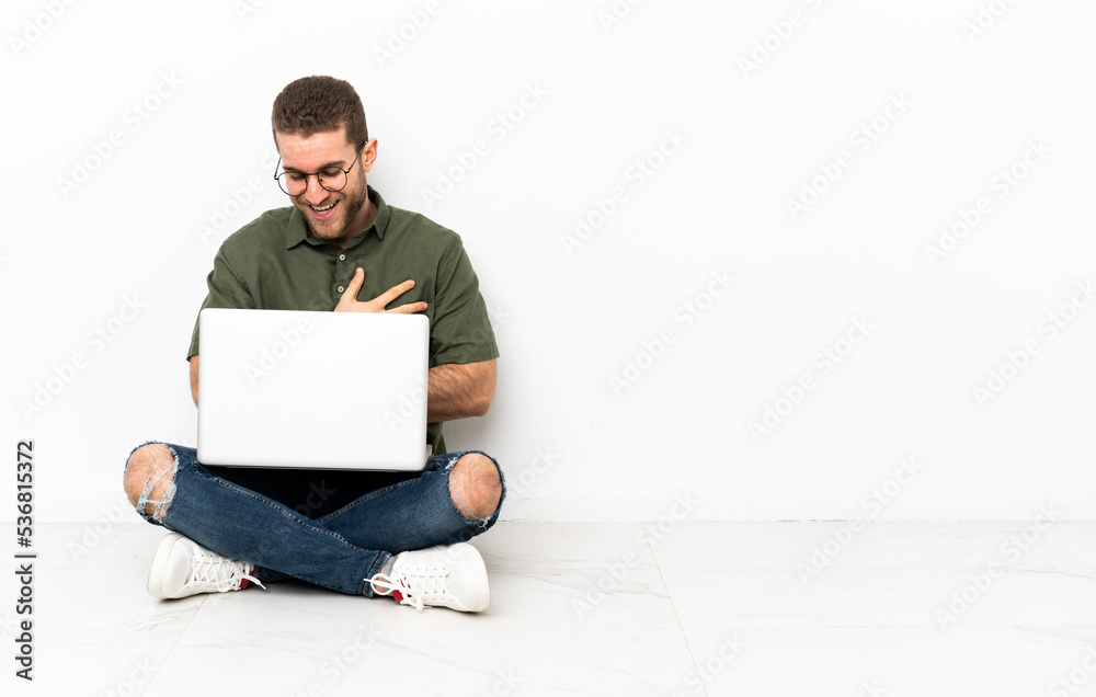 Young man sitting on the floor smiling a lot Young man sitting on the floor smiling a lot
