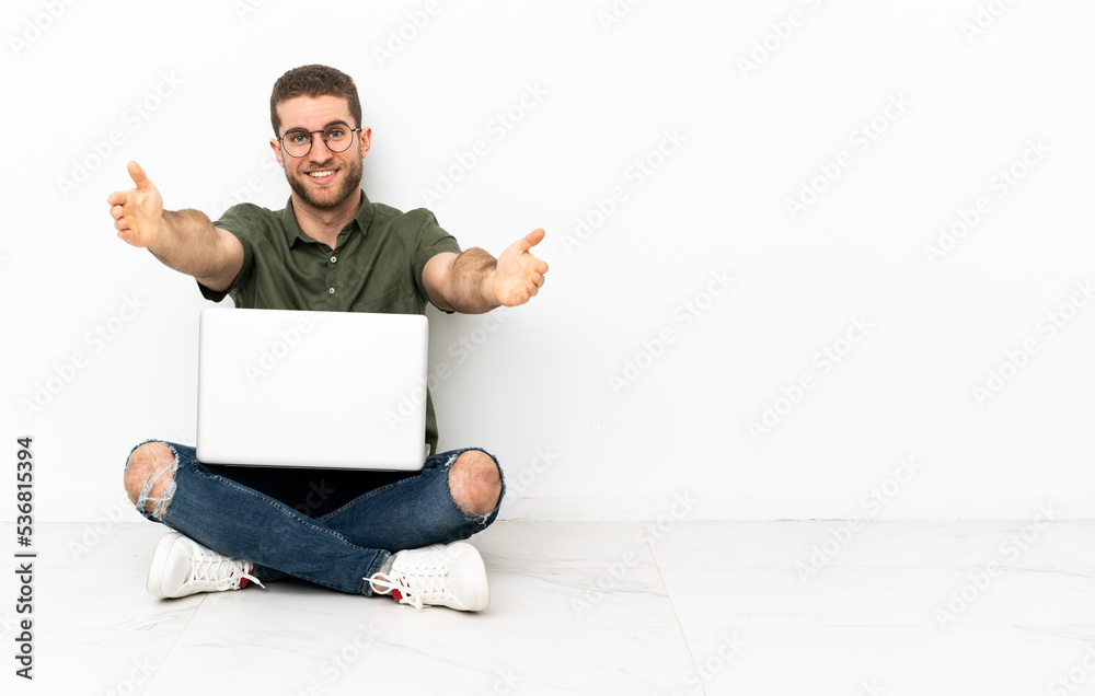 Young man sitting on the floor presenting and inviting to come with hand Young man sitting on the floor presenting and inviting to come with hand