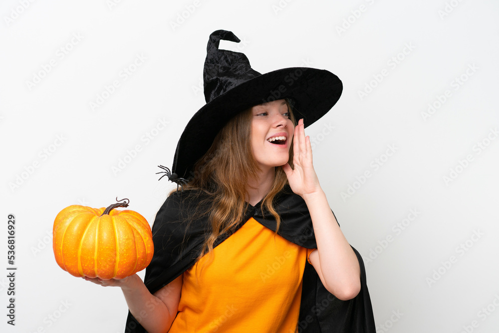 Young pretty woman costume as witch holding a pumpkin isolated on white background shouting with mouth wide open to the side Young pretty woman costume as witch holding a pumpkin isolated on white background shouting with mouth wide open to the side