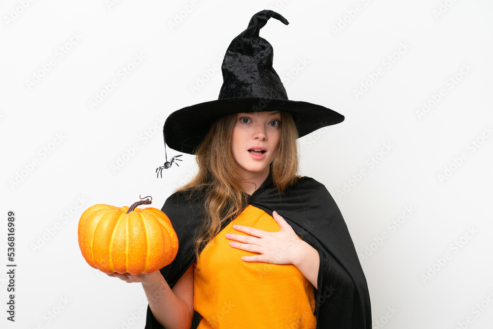 Young pretty woman costume as witch holding a pumpkin isolated on white background surprised and shocked while looking right Young pretty woman costume as witch holding a pumpkin isolated on white background surprised and shocked while looking right