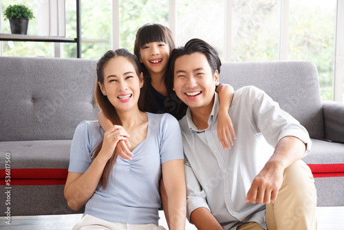 Close-up portrait of a happy young family. Mom, dad and daughter look at the camera and smile. The faces of Asian parents and their child.