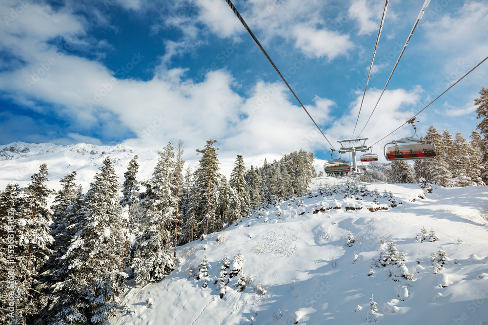 Sunny day at a ski resort. A ropeway over the forest