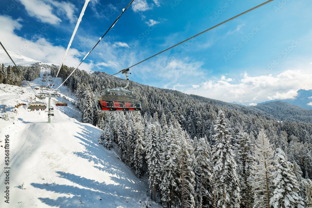 Sunny day at a ski resort. A ropeway over the forest