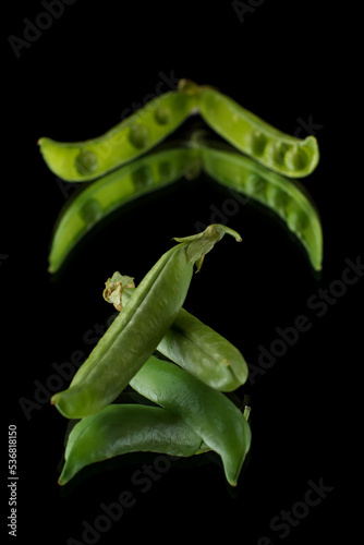 Pea pods on a black background, green peas in a pod