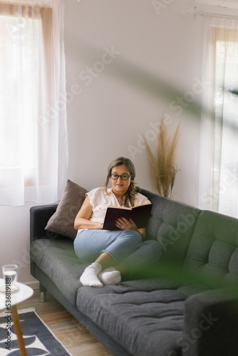 Lifestyle portrait of woman reading a book at home