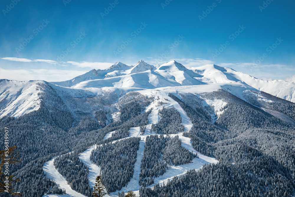 Panoramic view of the ski resort. Ski slopes and lifts passing through the forest