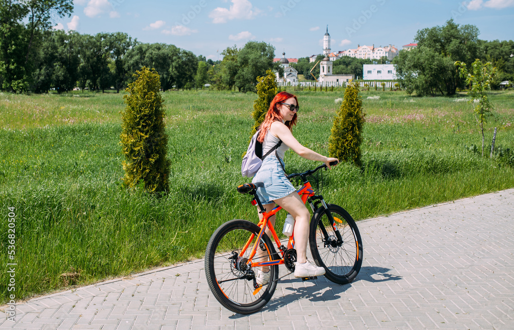Fototapeta premium Young woman in the city rides bike and leads an active lifestyle doing sports