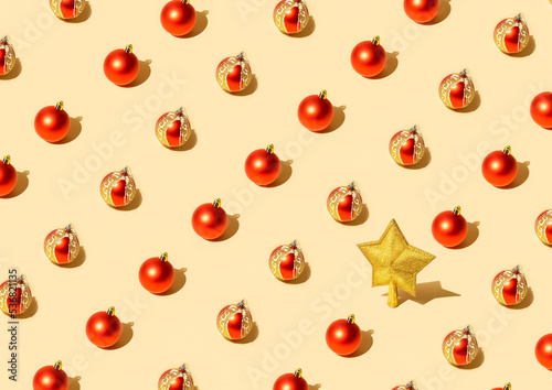 new year flat ley pattern with red baubles and golden star with glitter on pastel color background. minimal crative christmas composition.