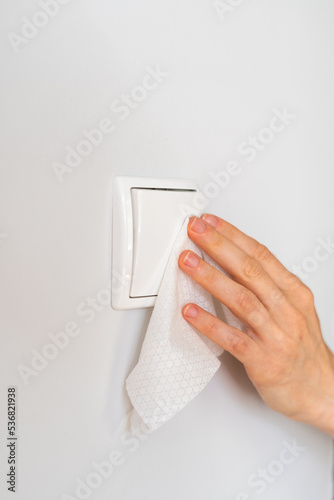 person cleaning light switch with wet wipe, closeup