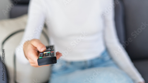 woman watching tv with remote control indoors