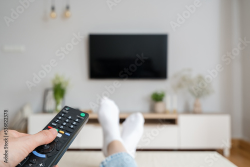 Fényképezés woman watching tv with remote control indoors