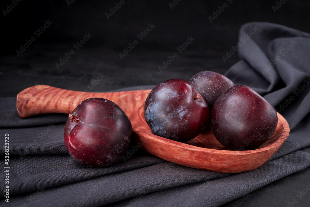 Obraz premium Fresh purple plum on black background