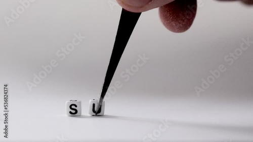 The phrase Summary appearing letter by letter on white background by a hand with a tweezers photo