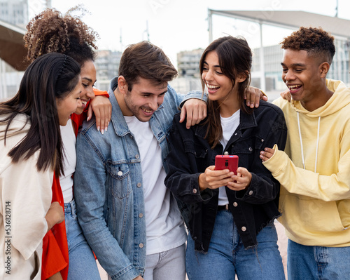 Group of young diverse smiling millennial friends looking at a mobile phone having a good time. having fun