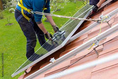 Workers installing solar panels on roof. Alternative energy concept.