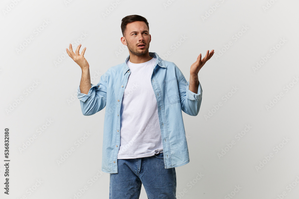 Fototapeta premium Confused thoughtful tanned handsome man in casual basic t-shirt raise hand up make difficult decision posing isolated on white studio background. Copy space Banner. Lifestyle People emotions concept