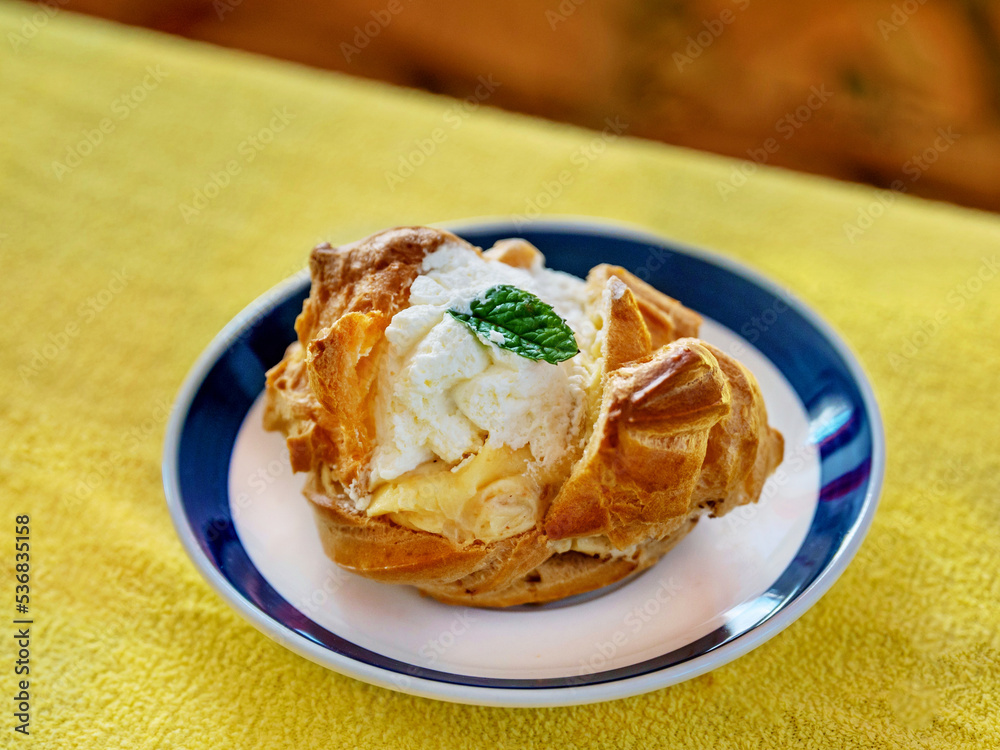 Light pastry dessert with whipped and caramel cream, small plate on yellow background.