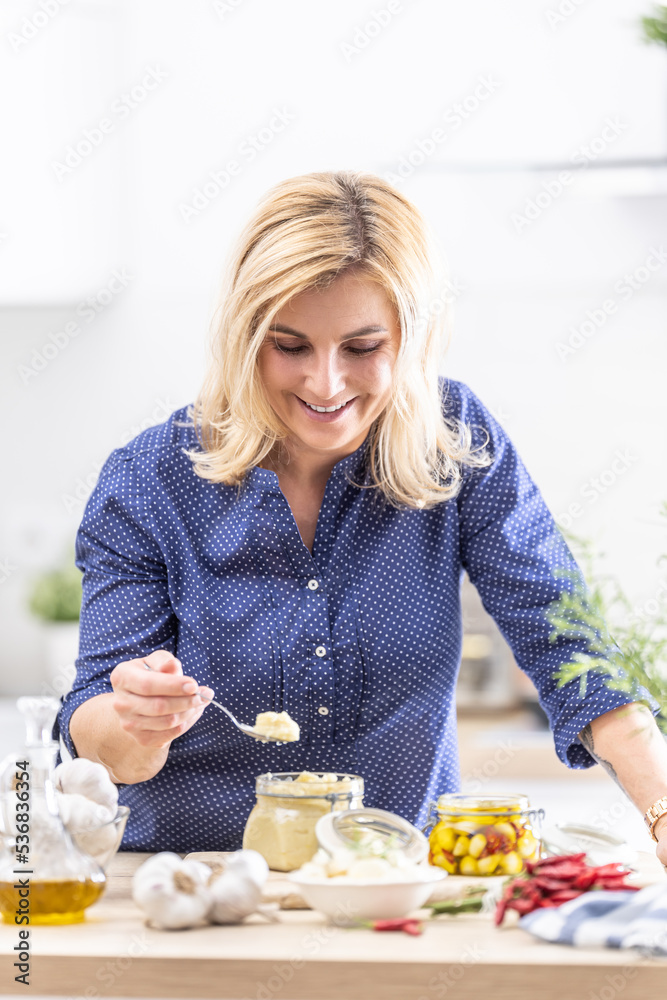 Housewife takes teaspoon full of crushed garlic from a preserve jar