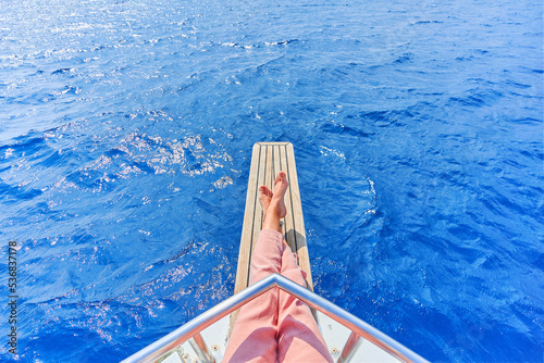 Legs of free carefree traveler girl while enjoying relaxing and calm private vacay on a boat in the turquoise sea © Goffkein