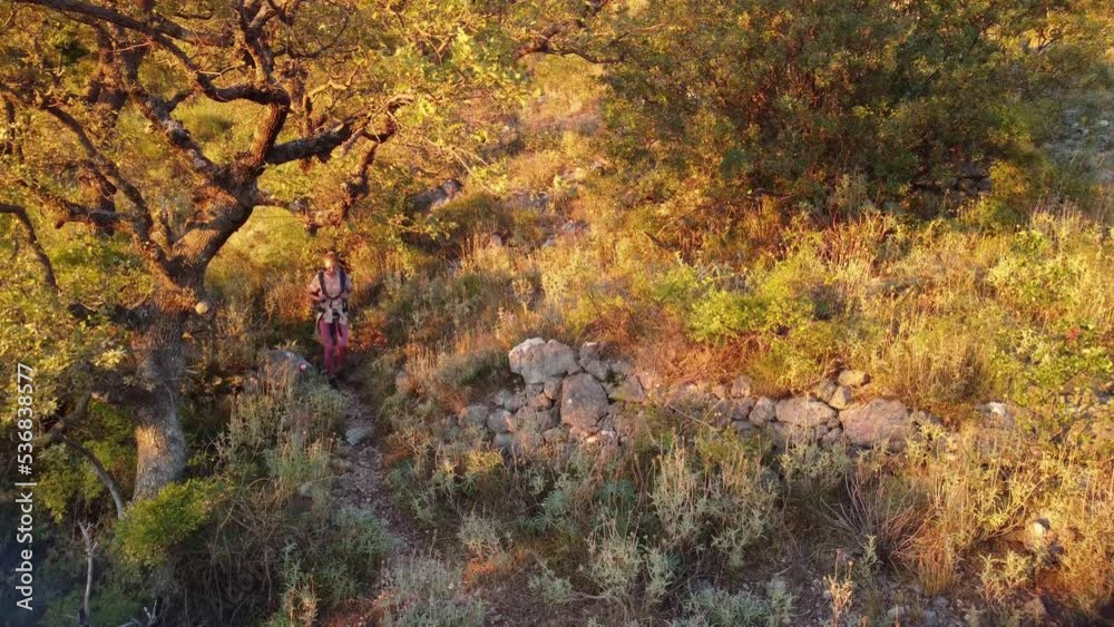 Drone video of young woman hiking on mountains in Europe. Beautiful autumn mountain nature in Montenegro at sunset. Female backpacker coming down from the mountains after a long walk in nature Drone video of young woman hiking on mountains in Europe. Beautiful autumn mountain nature in Montenegro at sunset. Female backpacker coming down from the mountains after a long walk in nature