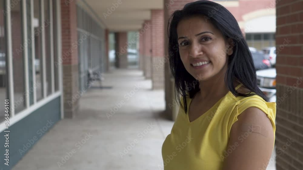 pretty indian woman smiles at camera with band aid on arm pretty indian woman smiles at camera with band aid on arm