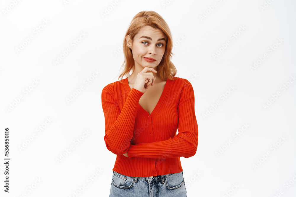 Image of young woman in red blouse, looking thoughtful, thinking of solution, pondering smth, standing over white background Image of young woman in red blouse, looking thoughtful, thinking of solution, pondering smth, standing over white background