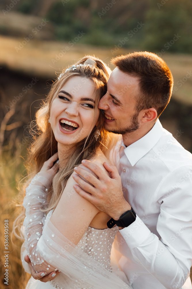 a cheerful couple in love, the bride and groom cheerfully and laughing meet the sunset a cheerful couple in love, the bride and groom cheerfully and laughing meet the sunset