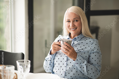 Cheerful attractive stylish lady enjoying her coffee break