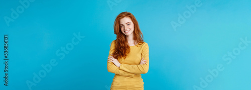 Portrait of young beautiful ginger woman with freckles cheerfuly smiling looking at camera. Isolated on pastel blue background. Copy space. photo