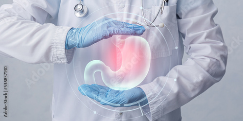 Doctor with stomach and different icons on virtual screen against grey background photo