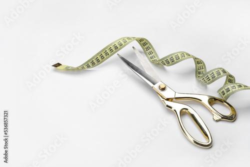 Scissors and measuring tape on white background