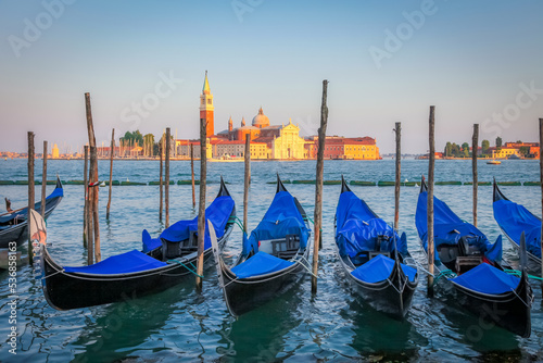 Gondole docked by wooden mooring poles in grand canal, Ethereal Venice, Italy © Aide