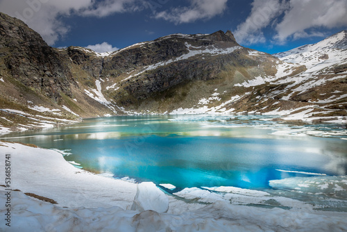 Alpine emerald lake melting and mountains at springtime, Gran Paradiso , Italy