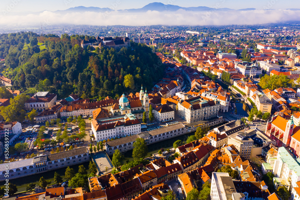 Panoramic aerial view of Ljubljana downtown with ancient castle complex on hilltop in sunny autumn morning, Slovenia