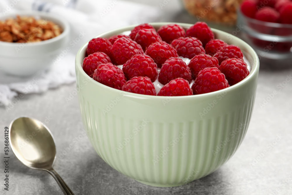 Bowl with delicious yogurt and raspberries on grey table, closeup Bowl with delicious yogurt and raspberries on grey table, closeup