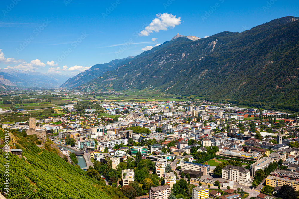 Summer view from drone of Martigny town in green valley on banks of Rhone river surrounded by Alps, Switzerland.