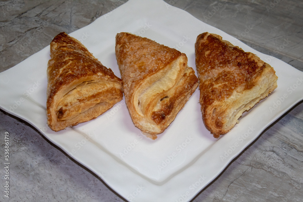 Three crispy apple turnovers on white plate Three crispy apple turnovers on white plate