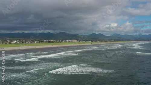 Aerial drone flight over ocean sea waves at small coastal beach town in Oregon.