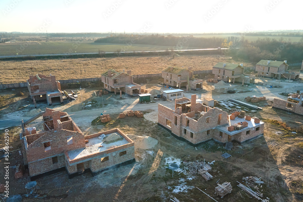 Aerial view of new homes with brick framework walls under construction in rural suburban area. Development of real estate in modern city suburbs