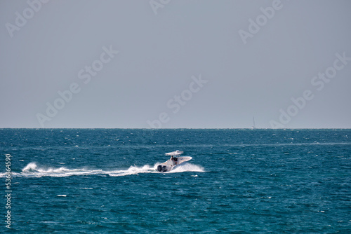 Seascape with ripple surface of blue sea water with white speedboat swimming fast on calm waves